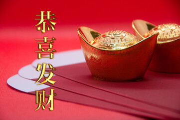 Chinese character - Gong Xi Fa Cai text with gold ingot and red packet on red background. Chinese New Year celebration concept.