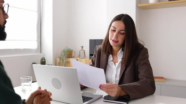 Young business woman interviewing a young man. Male job candidate giving resume to company recruiter at office. Human resources and recruitment concept