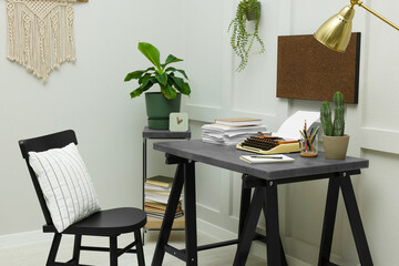 Typewriter and stack of papers on dark table in room. Writer's workplace