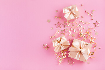 Gift or present boxes, golden ribbons and stars confetti on pink table top view. Flat lay festive composition for birthday or Christmas.