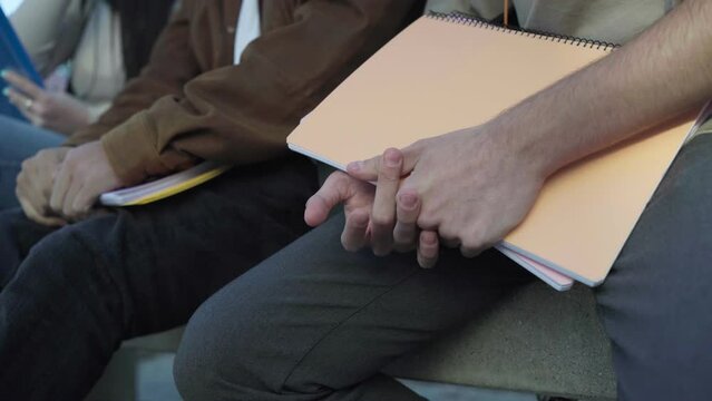 close up of the hands of some students sitting in a university campus.