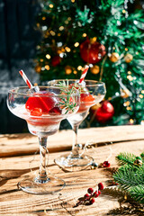 Christmas refreshment drink mimosa, punch or cranberry margarita cocktail serving in christmas ornaments and martini drinking glasses. Delicious icy drink idea for christmas and winter holiday party.