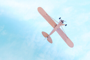 Retro plane with propeller flying and dives against the blue sky