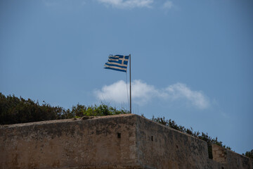 A Greek flag flies on top of a fortress