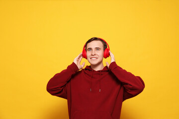 Fototapeta premium Handsome young man with headphones on yellow background