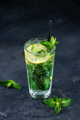 mojito cocktail with mint, ice and lemon. Fresh cocktail in glass on dark background
