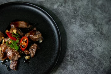 Gordijnen Korean Galbi Jjim, braised short ribs with spring onion and pepper in black plate on dark background © Metanoiamoments/Wirestock Creators