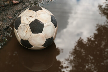 Fototapeta premium Dirty soccer ball in muddy puddle, space for text