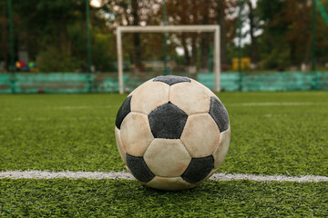 Dirty soccer ball on green football field