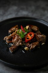 Closeup shot of Korean Galbi Jjim, braised short ribs with spring onion and pepper in black plate