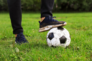 Man with dirty soccer ball on green grass outdoors, closeup
