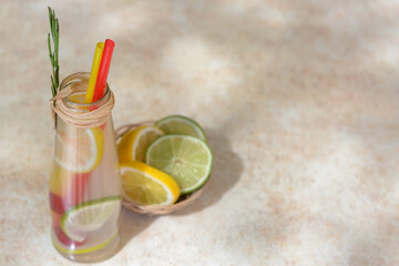 Refreshing tasty lemonade served in glass bottle and citrus fruits on beige table. Space for text