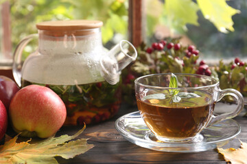 Hot tea, apples and dry leaves on wooden windowsill. Autumn atmosphere