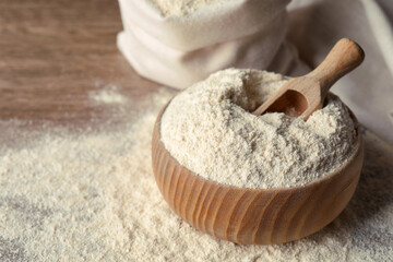 Wooden bowl with quinoa flour and scoop on table. Space for text