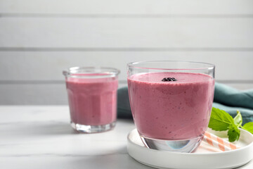 Glasses of blackberry smoothie with mint on white table, space for text