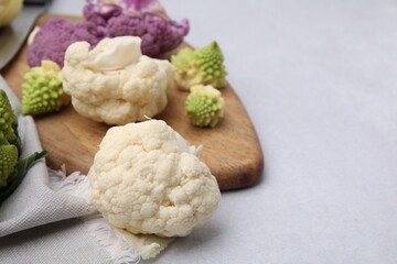 Various cauliflower cabbages on light grey table, space for text