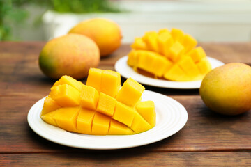 Delicious ripe cut and whole mangos on wooden table