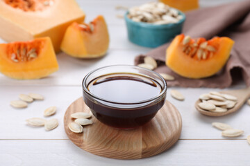 Glass bowl of fresh pumpkin seed oil on white wooden table