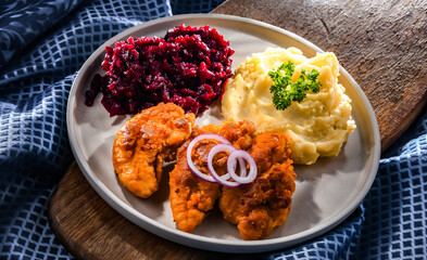 Breaded chicken cutlets served with potatoes and beetroot