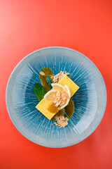 Raw coconut cream lemon cake garnished with lemon slices and almonds and mint sauce.