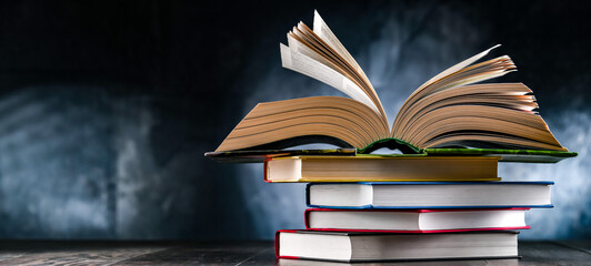 A composition with an open book lying on a stack of other books