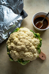 Whole cauliflower head with herbs and spices. Cooking process, top view.