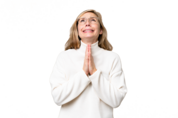 Young blonde woman over isolated background keeps palm together. Person asks for something