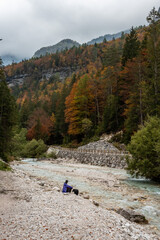 A hiker resting with his dog at a lake in the Bistrice valley, enjoying the view on the Julian Alps