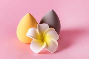 Yellow and Gray Make Up Blender Puff Eggs for Make Up and Flower Pink Background Horizontal
