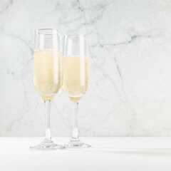 Christmas festive background with two sparkling champagne wine glass in modern white bar interior with marble, copy space, square. Holiday beverage for congratulations and party. - obrazy, fototapety, plakaty