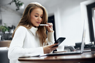 Image of beautiful  woman smiling and using cellphone. Girl working with laptop