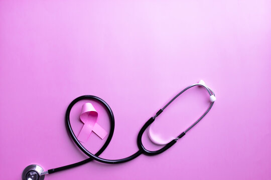Flat lay of pink ribbon bow with stethoscope on pink background to encourage breast cancer patient. Breast cancer campaign in October month