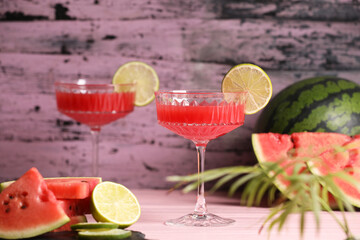 Cocktail glass of delicious fresh watermelon juice with lime on light wooden table