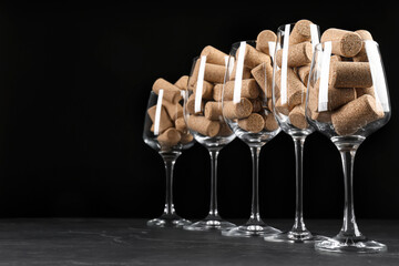 Glasses full of wine corks on black table. Space for text