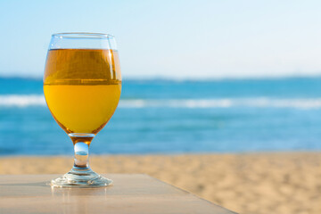 Glass of cold beer on wooden table at beach. Space for text