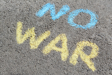 Words No War written with blue and yellow chalks on asphalt outdoors