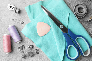 Flat lay composition with scissors, spools of threads and sewing tools on light grey background