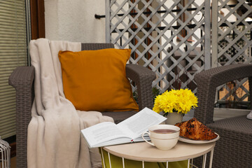 Pillow, blanket and beautiful chrysanthemum flowers on garden furniture outdoors