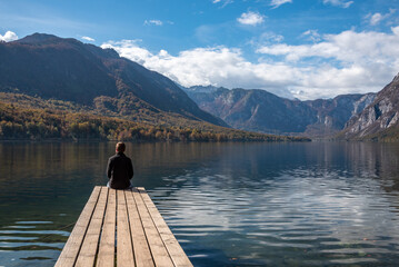 Sitting on a small jetty and enjoying the view on the landscape of lake Bohinj in the Triglav...