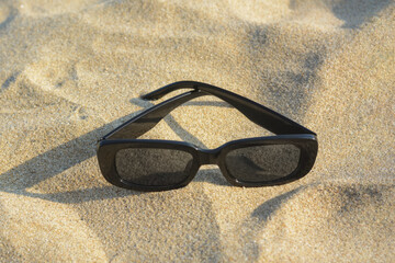 Stylish sunglasses on sandy beach, closeup. Space for text