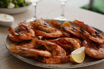 Plate of delicious cooked shrimps served with lemon and wine at table, closeup