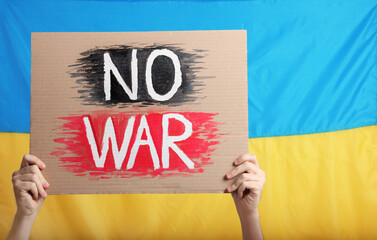 Teenage boy holding poster No War against Ukrainian flag, closeup. Space for text