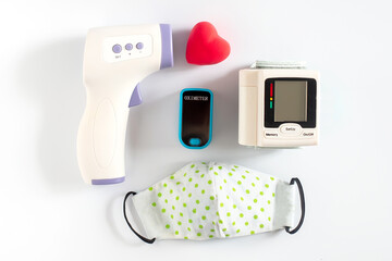 infrared contactless thermometer next to voluminous heart on white background with trend shadows....