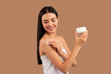 Pretty long-haired woman applying body cream on shoulder, copy space