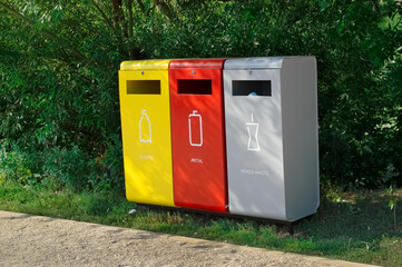 garbage cans - yellow, red, gray with separation into types of garbage stand by the sidewalk