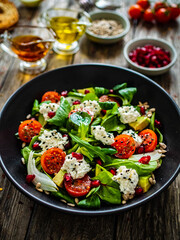 Fresh vegetable salad with feta cheese and pomegranate  on wooden table
