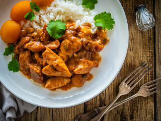 Fried chicken nuggets in peach sauce with white rice on wooden table
