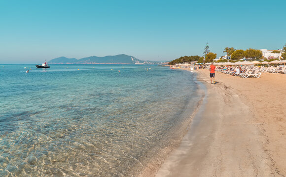 paisaje de playa con aguas turquesas, en Cala Martina,Ibiza,España, con turistas descansando en hamacas o corriendo en la orilla del mar
