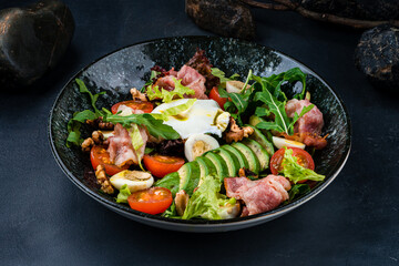 Lunch salad of avocado, poached eggs, bacon, quail eggs, tomatoes, arugula and lettuce.