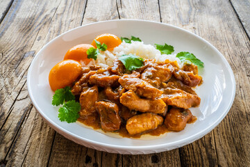 Fried chicken nuggets in peach sauce with white rice on wooden table
